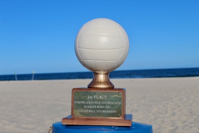 The first-place trophy on the sand with the ocean behind it