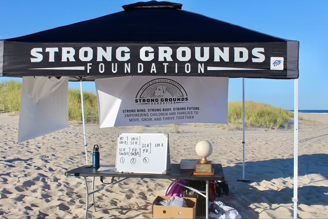 The Strong Grounds Foundation tent, bracket board, and trophies on the sand